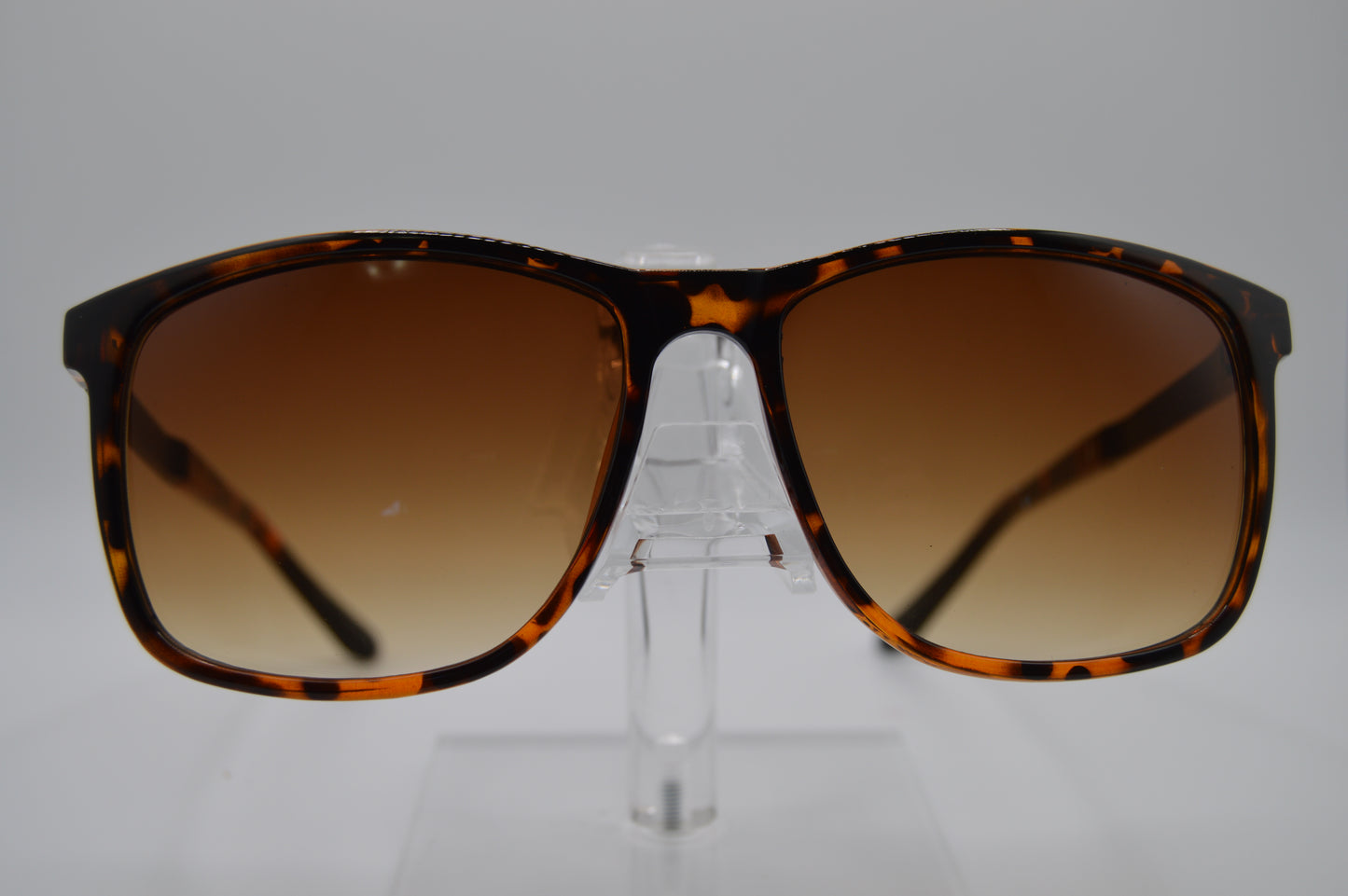 Sunglasses with tortoiseshell frame and brown gradient lenses on a gray background